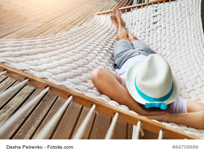 Man in hat in a hammock on a summer day